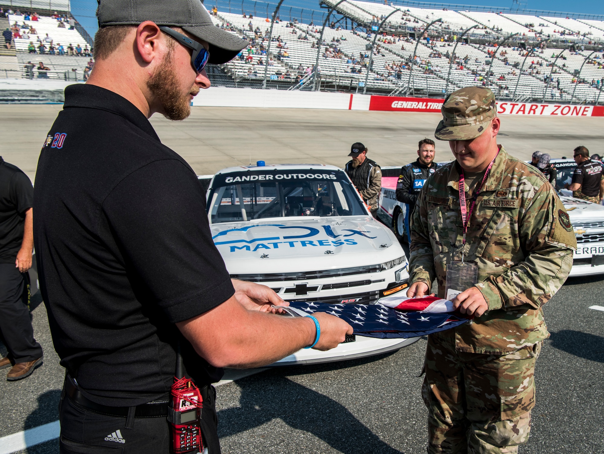 Joshua Aultice, Spencer Boyd Racing Public Relations Manager, and Staff Sgt. Kyle Leidholm, 436th Aircraft Maintenance Squadron C-5 Super Galaxy crew chief, fold an American flag after the National Anthem May 3, 2019, at the Dover International Speedway in Dover, Del. The flag is folded into the shape of a triangle to represent a tri-cornered hat worn by colonial soldiers. This shape is meant to remind race attendees of the freedoms and privileges earned from the sacrifice of many service members. (U.S. Air Force photo by Senior Airman Christopher Quail)