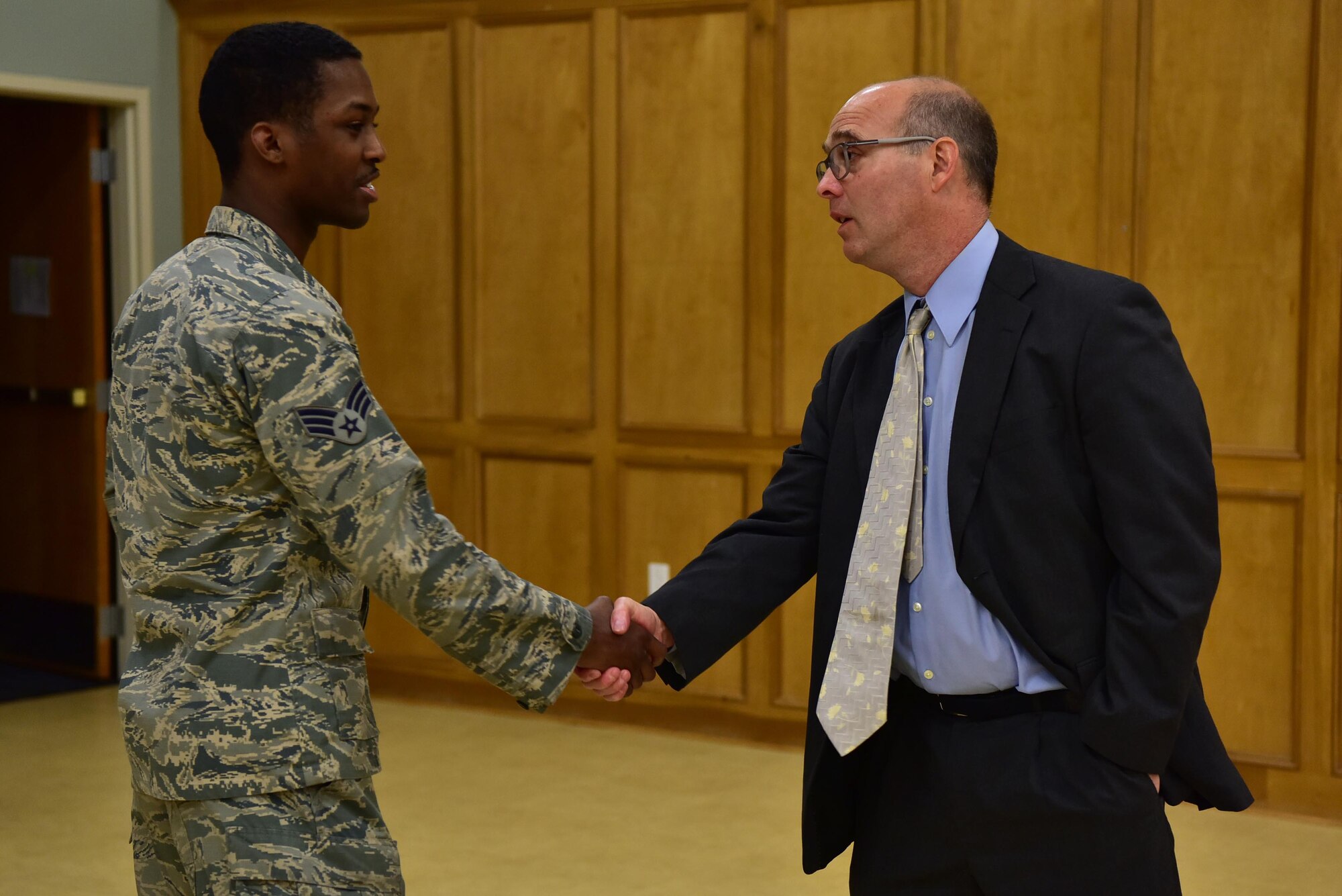 An Airman shakes the hand of the guest speaker during a Holocaust rembrance service.