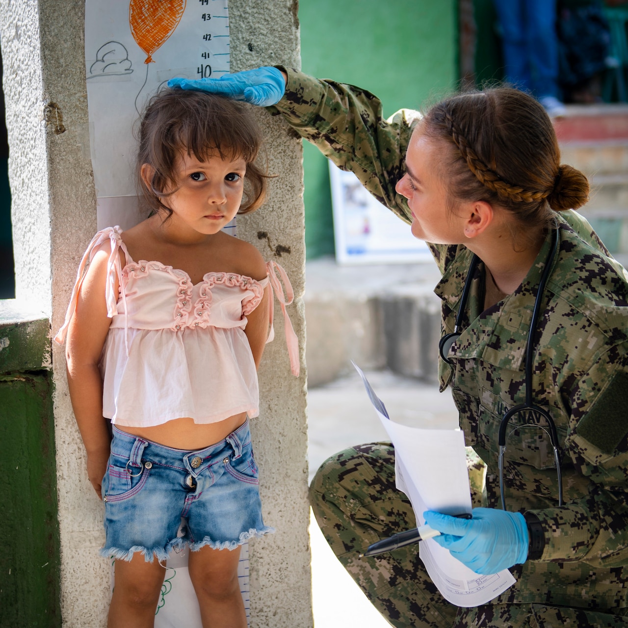 A sailor measures a girl's height.