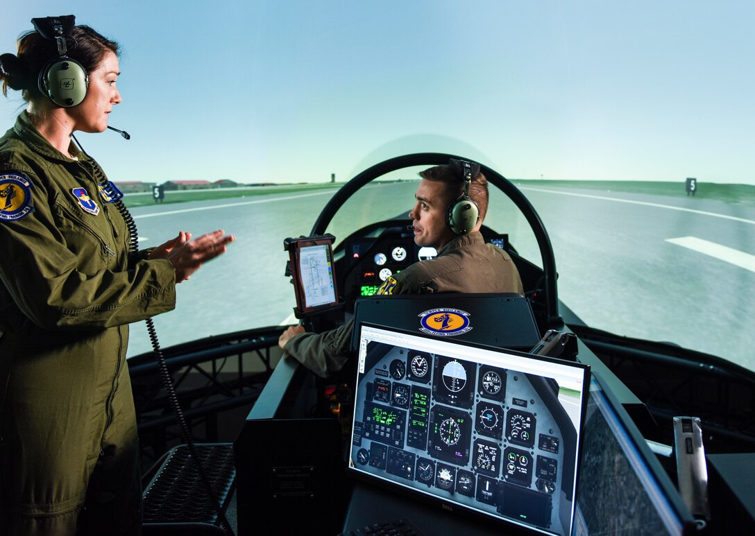 Commander of 558th Flying Training Squadron, left, discusses training mission utilizing T-6 Flight Simulator with enlisted remotely piloted aircraft pilot student, Joint Base San Antonio, Texas, July 17, 2018 (U.S. Air Force/Bennie J. Davis III)