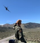 An Air National Guard member from the 192nd Airlift Squadron watches as a Nevada Air National Guard C-130 flies over the Naval Air Station Fallon Range Training Complex during the Resolute Hunter Exercise, a joint exercise with the U.S. Navy, Nevada Air National Guard and Nevada Army National Guard on April 25, 2019.