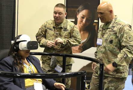 MSB Exhibitors Sgt. 1st Class Daniel Carpenter (center) and Sgt. 1st Class Ty Ramon (right) guide a participant through a 360 degree interactive display focused on tandem skydiving with the Army Parachute Team.