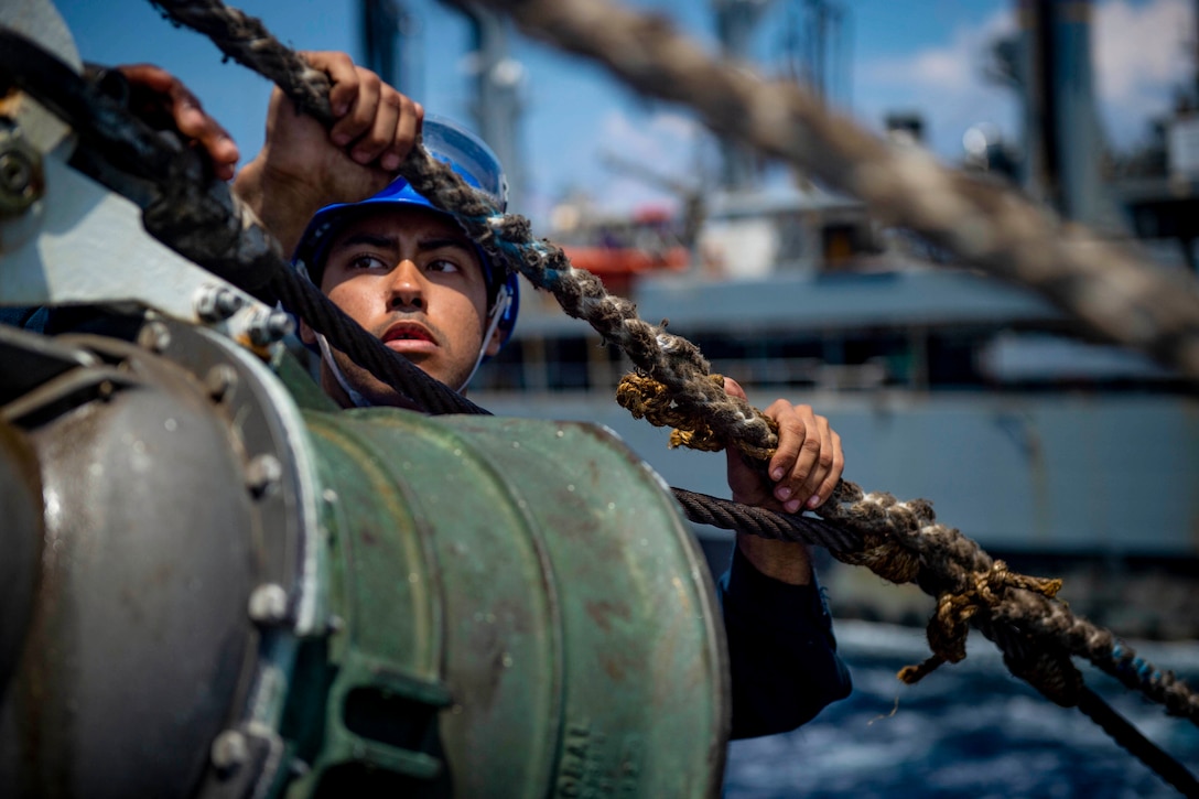 A sailor grabs onto a rope with two hands.