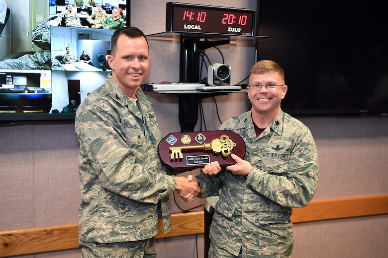 Lt. Col. Armon Lansing (right), 4th Space Operations Squadron commander, accepts the key from Col. David Ashley, Space and Missile Center AEHF program manager, signifying the handoff of the Advanced Extremely High Frequency-4 satellite to the 4th SOPS at Schriever Air Force Base, Colorado, May 3, 2019. AEHF-4 joins the squadrons other military satellite communication satellites supporting space and intelligence, nuclear and defense, theater mission defense and special operations. This is the fourth satellite the squadron commands and controls, with two more launces planned. (U.S. Air Force photo by Kathryn Calvert)