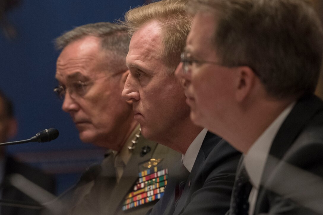 Three defense leaders sit together at a table.