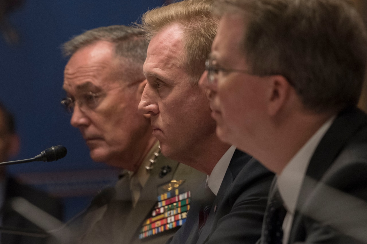 Three defense leaders sit together at a table.