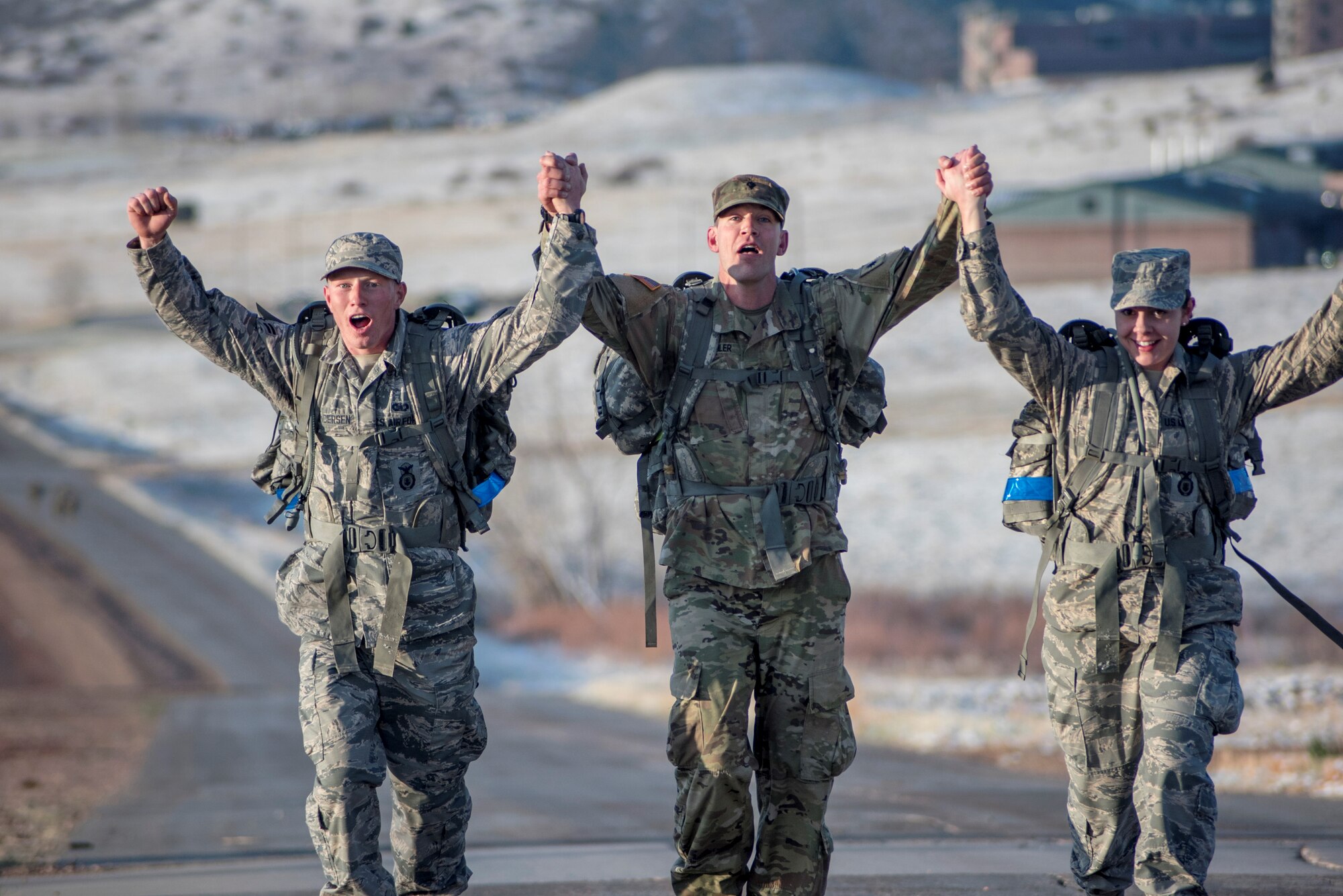 3 participants in the Best Warrior Competition hold hands high in victory