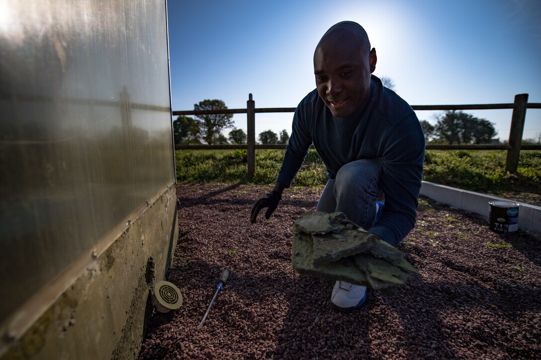 U.S. Air Force Capt. Claude Betene A Dooko, 435th Contingency Response Support Squadron air advisor flight commander, picks up concrete slabs scraped off a weathered pedestal as part of a WWII memorial beautification project in Picauville, France, May 30th, 2019. Betene was the interpreter for the 435th Construction Training Squadron, providing translations between them and the French. He also helped the Airmen leading the project clean the memorial. (U.S. Air Force photo by Staff Sgt. Devin Boyer)