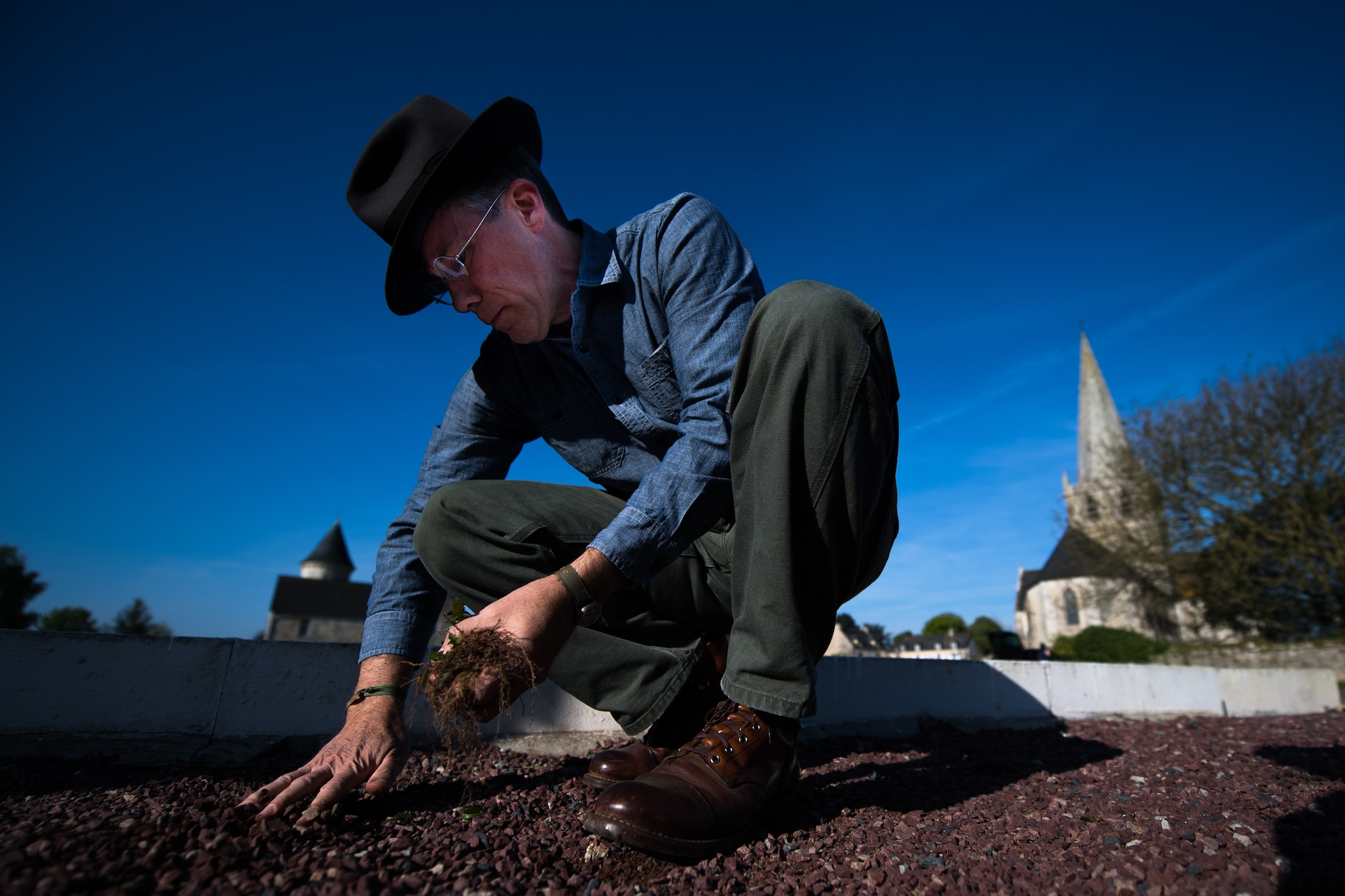 Dr. Jeffrey McGovern, 435th Air Ground Operations Wing historian, pulls weeds out of a WWII memorial in Picauville, France, April 30, 2019. After the project to refurbish the memorial was complete, McGovern gave a tour of the crash sites of U.S. aircraft that went down during D-Day. (U.S. Air Force photo by Staff Sgt. Devin Boyer)