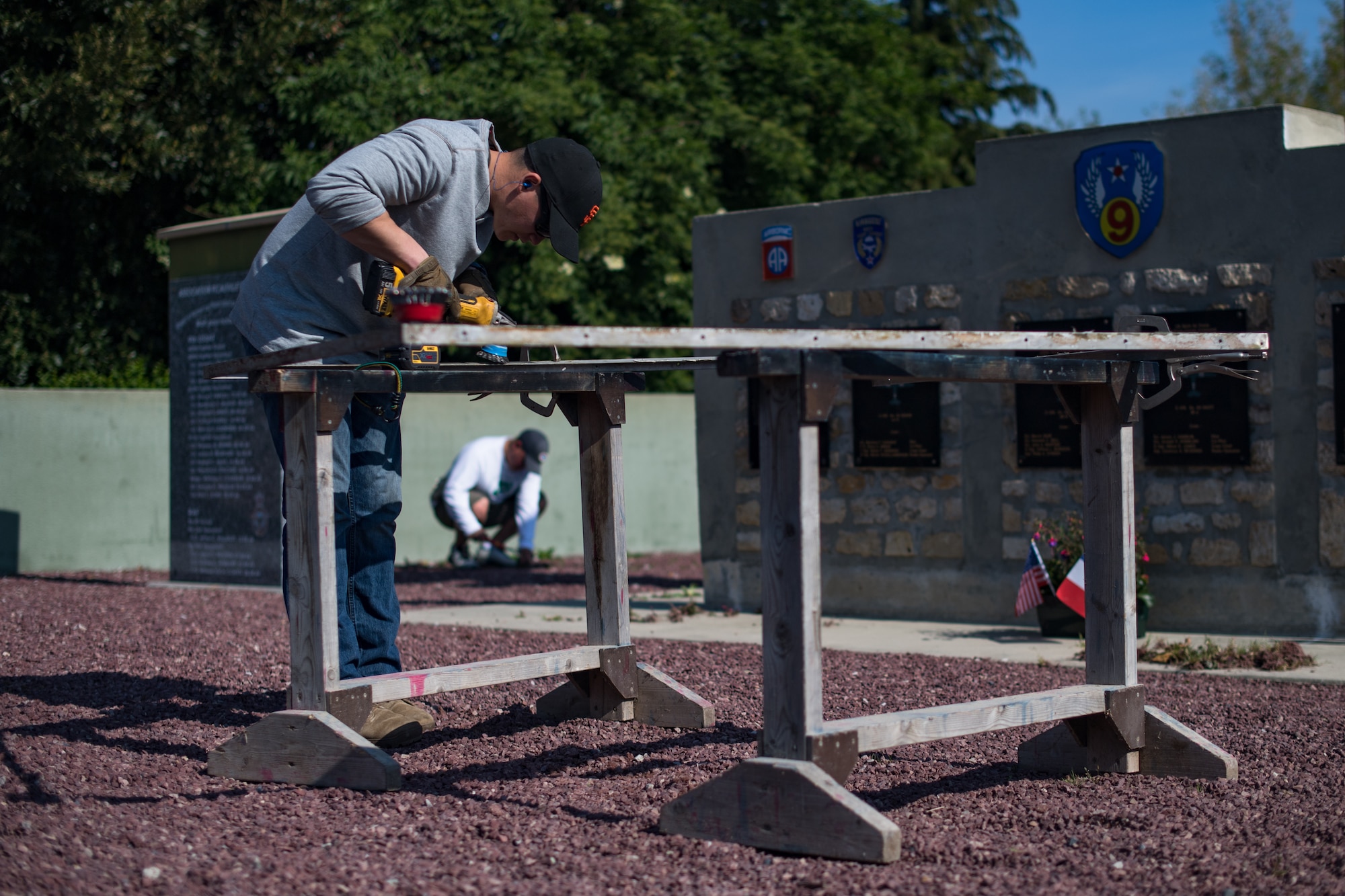 U.S. Air Force Staff Sgt. Matthew Evans, 435th Construction Training Squadron structural contingency instructor, brushes a metal frame at a WWII memorial in Picauville, France, April 30, 2019. The frame was used to anchor a display case holding an aircraft engine that was shot down on D-Day. (U.S. Air Force photo by Staff Sgt. Devin Boyer)