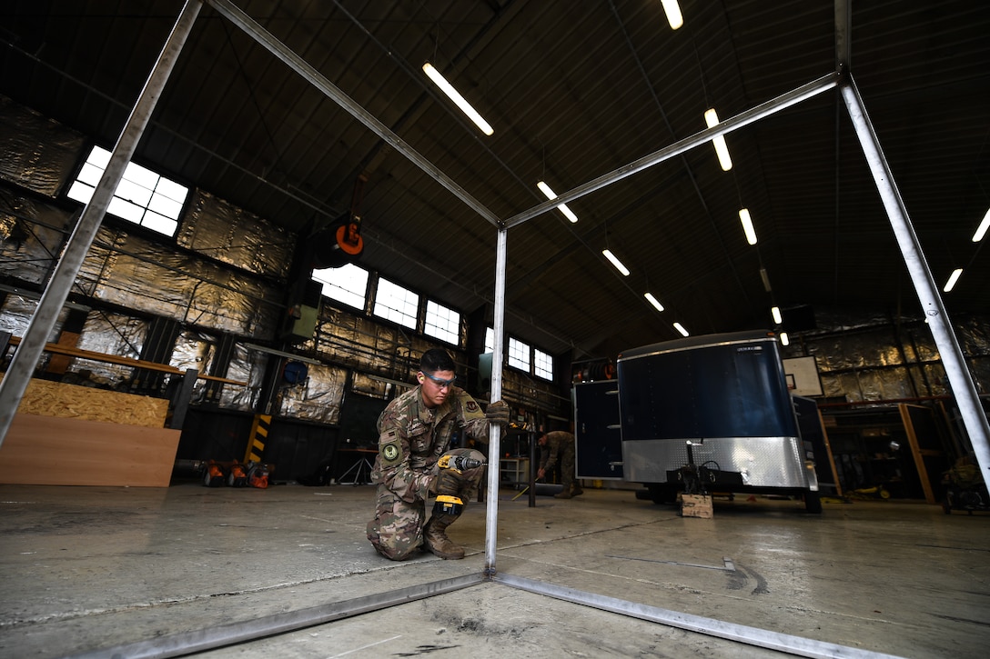 U.S. Air Force Staff Sgt. Matthew Evans, 435th Construction Training Squadron structural contingency instructor, drills holes into a metal frame at the 435th CTS compound near Ramstein Air Base, Germany, April 26, 2019. The frame replaced a display case holding a WWII aircraft engine at a memorial in Picauville, France. (U.S. Air Force photo by Staff Sgt. Devin Boyer)