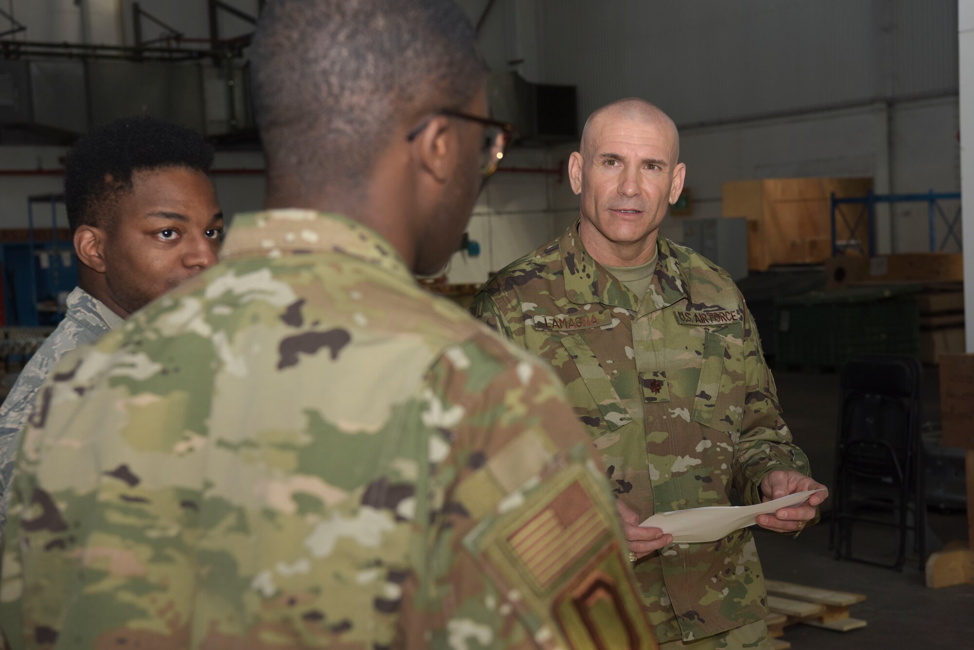 U.S. Air Force Senior Airman Kentral White and Airman 1st Class Jaquavius Johnson, 100th Logistics Readiness Squadron traffic management journeymen, and Maj. Anthony LaMagna, 100th Logistics Readiness Squadron commander, discuss shipping orders for an outbound package at RAF Mildenhall, England, May 2, 2019. LaMagna participates in ‘Walking with Warriors’ once a week, where all leadership leave their desk and interact with Airmen, from top leadership on down.   (U.S. Air Force photo by Senior Airman Alexandria Lee)