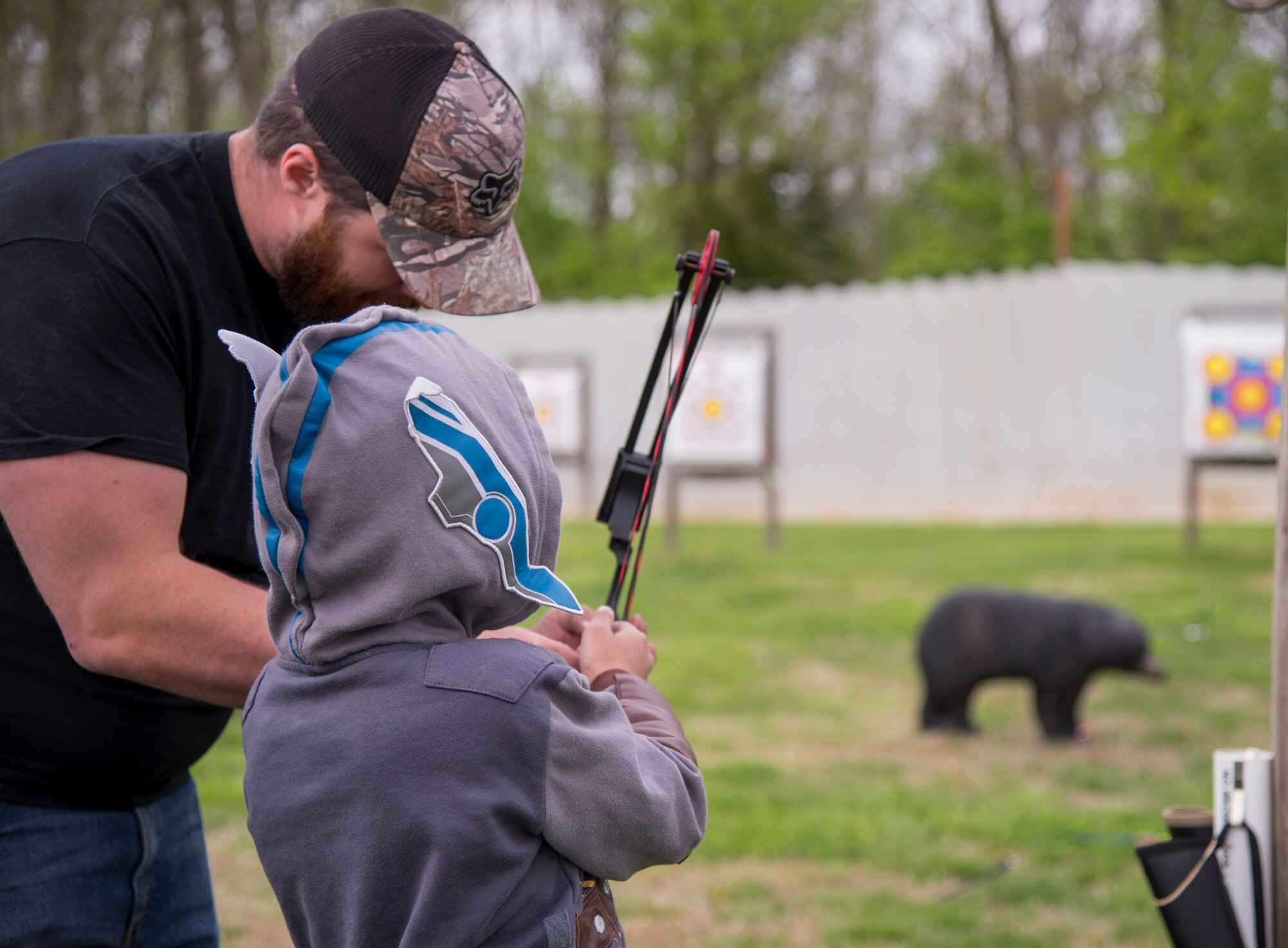 Man helping child with archery bow.