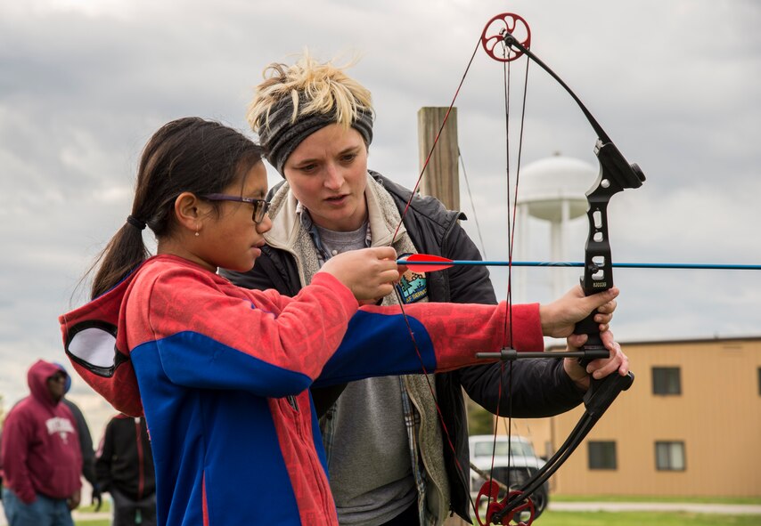 Woman helping child with archery bow.