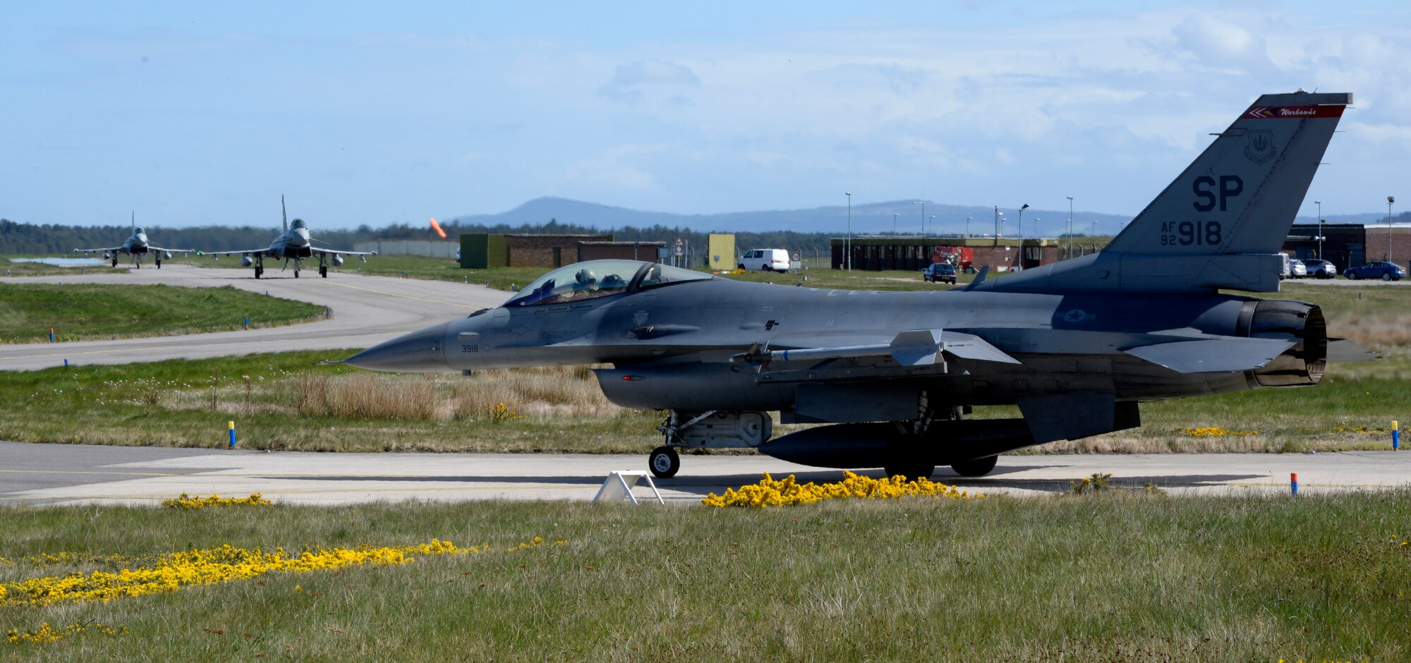 An F-16 Fighting Falcon from the 480th Fighter Squadron, 52nd Fighter Wing, Spangdahlem Air Base, Germany, waits for a pair of Royal Air Force Eurofighter Typhoons to taxi by before a low-level training sortie at RAF Lossiemouth, Scotland, May 7, 2019, during exercise Formidable Shield. Formidable Shield is a U.S.-led exercise, conducted by Naval Striking and Support Forces NATO. The purpose of the training is to improve allied interoperability in a live-fire integrated air and missile defense exercise. (U.S. Air Force photo by Master Sgt. Austin M. May)