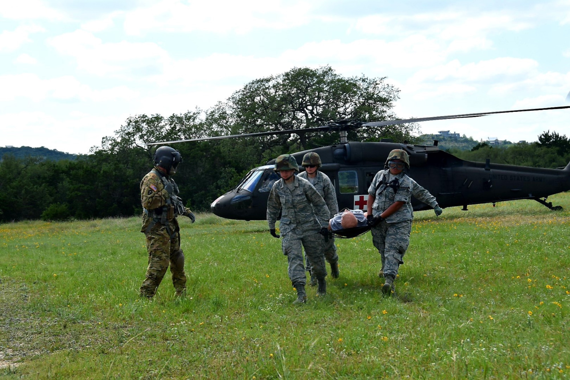 Sgt. 1st Class Dion Cortez, Company C, 2-149 Aviation Texas Army National Guard flight medic, guides Reserve Citizen Airmen medical technicians off-loading a simulated wounded patient by stretcher during Operation Joint Medic May 5, 2019 at Joint Base San Antonio-Camp Bullis, Texas.