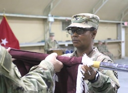 Col. Betty Demus, 349th Combat Support Hospital commander, uncases the unit's colors during a transfer of authority ceremony for United States Military Hospital-Kuwait at Camp Arifjan, Kuwait, May 6, 2019.