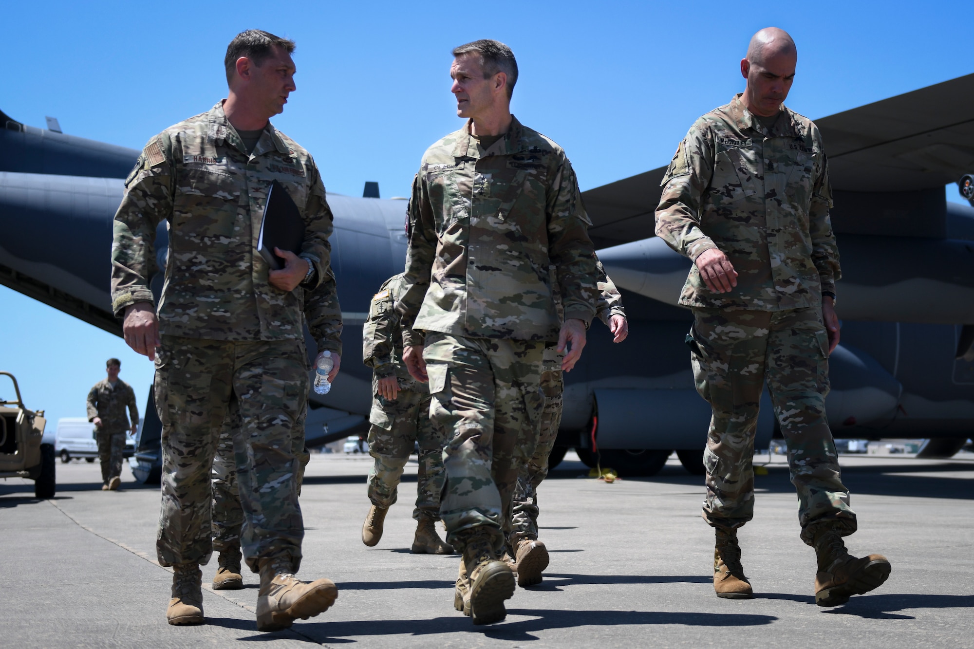 Three people walking on a flightline.