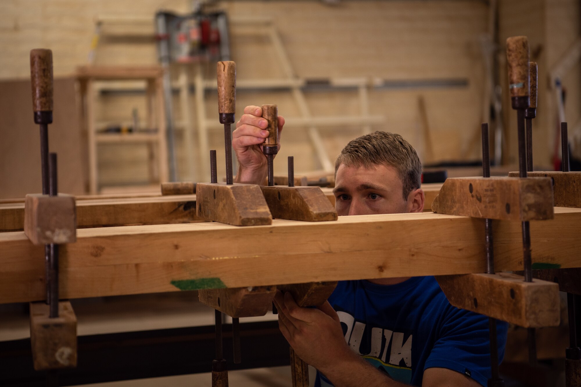 U.S. Air Force Staff Sgt. Thomas Johnson, 56th Component Maintenance Squadron weapons load crew chief, uses clamps and glue to join two pieces of wood together May 4, 2019, at Luke Air Force Base, Ariz.