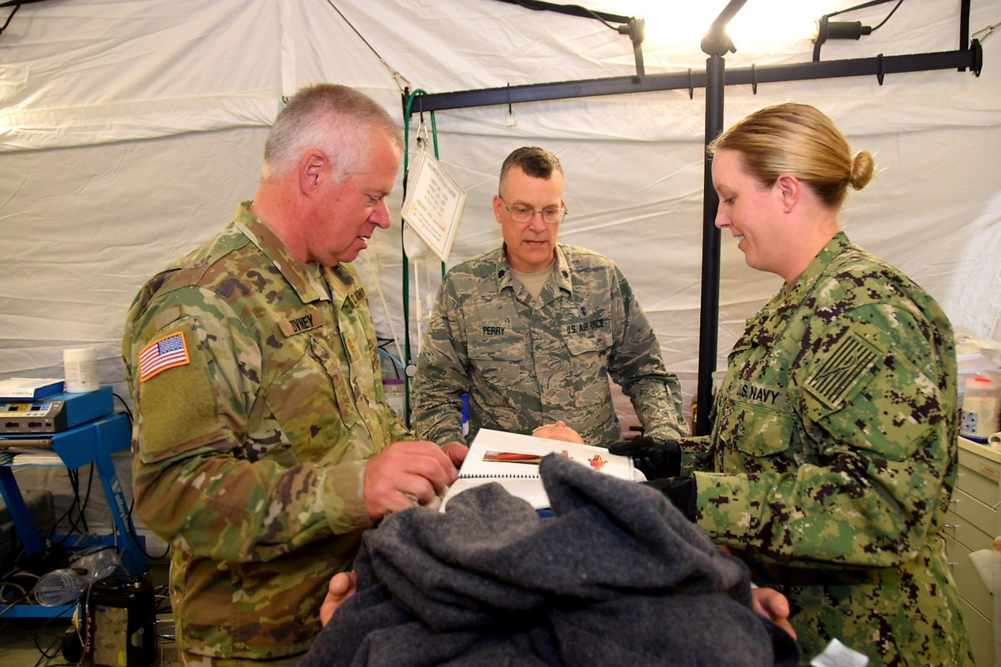 Maj. (Dr.) Ben Zivney, Army 7454th Medical Backfill Battalion surgeon, reviews the chart on a simulated patient with Lt. Col. James Perry, 433rd Medical Squadron nurse anesthetist, and Lt. j.g. Sherry Kidd, Navy Expeditionary Medical Facility Dallas surgical nurse, during Operation Joint Medic May 5, 2019 at Joint Base San Antonio-Camp Bullis, Texas.