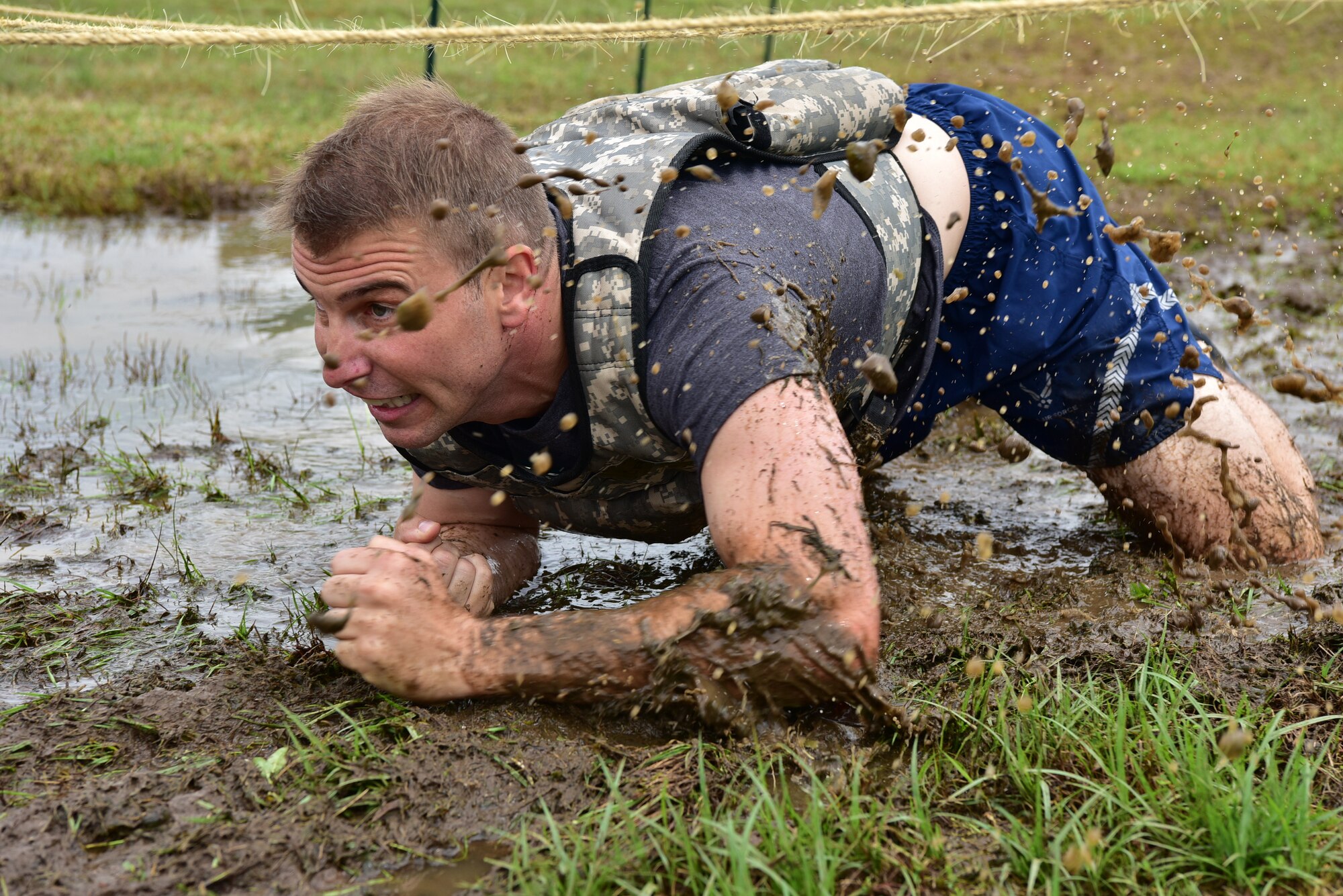 An Airman low crawls through the mud during the SAPR CLEAR challenge.