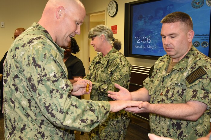Navy Lt. Timothy Delaughter, chaplain, left, blesses the hands of Naval Health Clinic Charleston nurse and interim director of NHCC Healthcare Business, Lt. Cdr. Mike Cornell, during a "Blessing of the Hands" ceremony May 7, 2019, at NHCC located on Joint Base Charleston - Weapons Station, S.C., in celebration of National Nurses Week May 6-12