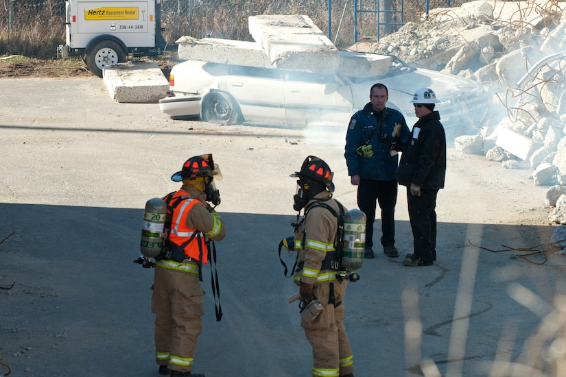 Firefighters look at a demolished building.