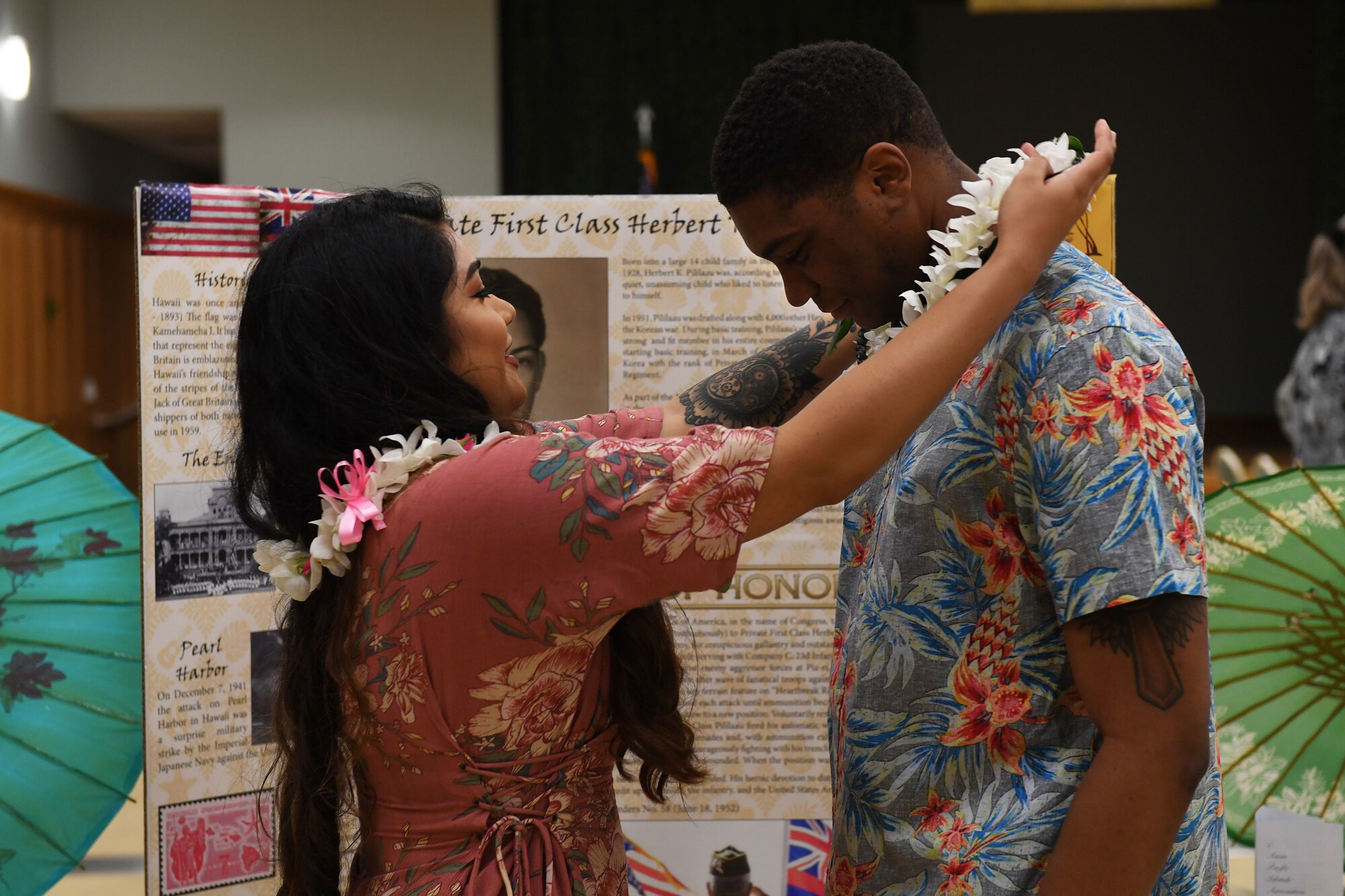 A woman places a lei on around a man's neck.