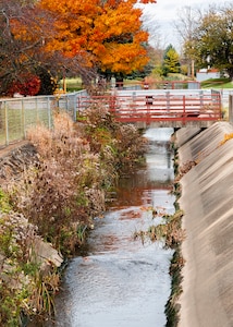 Picture of water, a bridge and trees changing colors