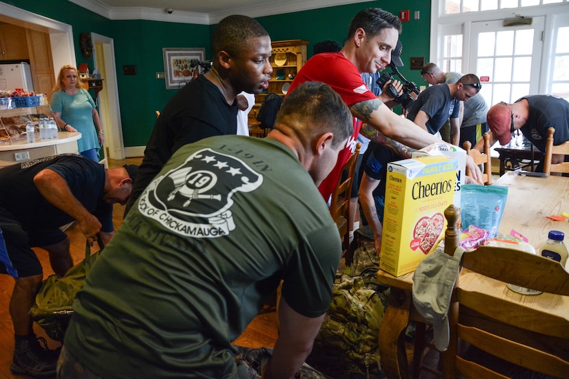 People gather donated goods, including a box of Cheerios.