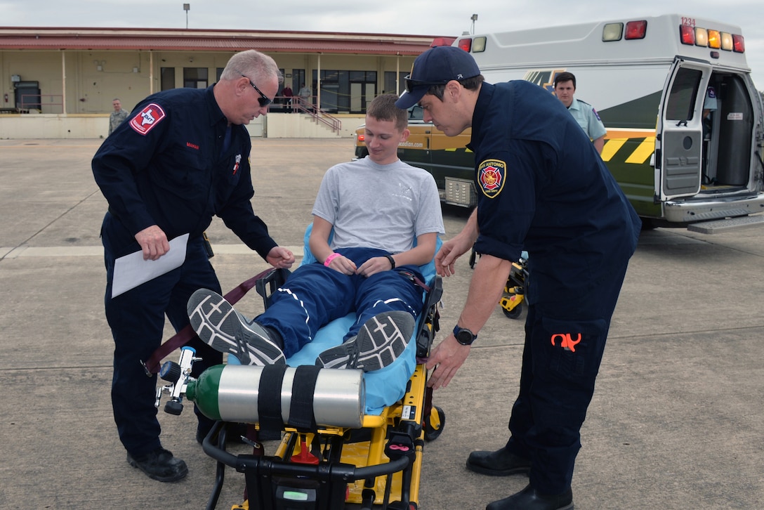 Paramedics tend to a man on a stretcher as an ambulance awaits in the background.