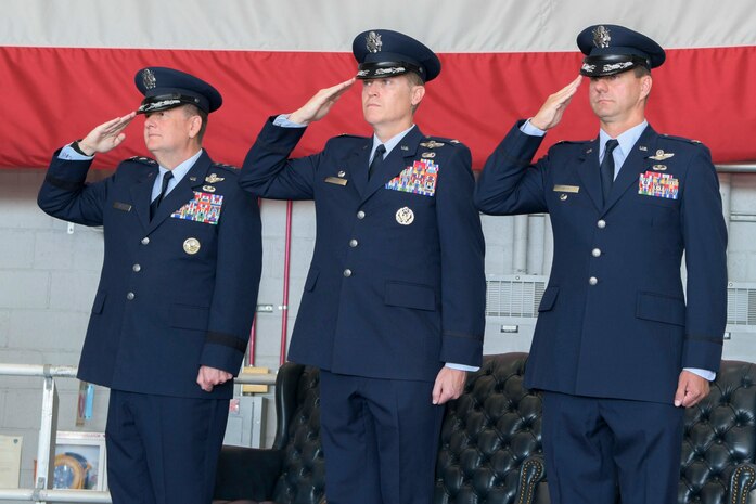 Three people rendering salutes at an event.