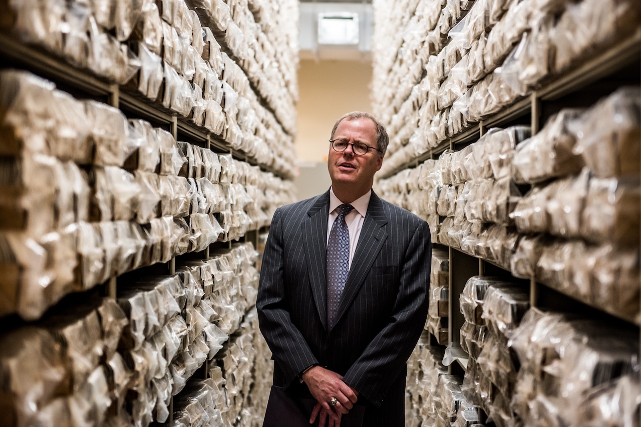 A person stands in the middle of two ceiling-high rows of files.