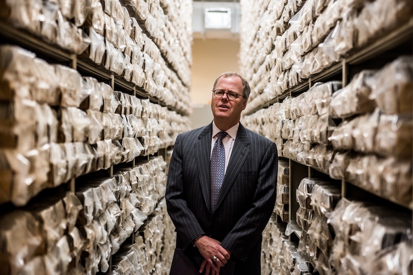 A person stands in the middle of two ceiling-high rows of files.