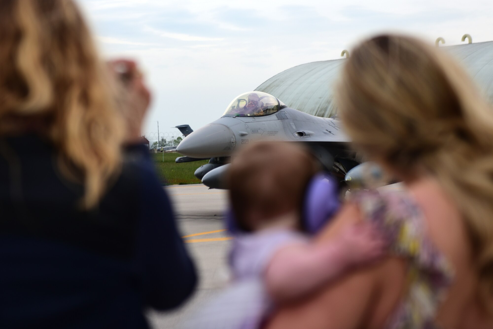 A family eagerly awaits an Airman assigned to the 510th Fighter Squadron to de-board his F-16 Fighting Falcon at Aviano Air Base, Italy, April 30, 2019. The 510th FS plays an integral role in national security at Aviano AB. (U.S. Air Force photo by Senior Airman Kevin Sommer Giron)