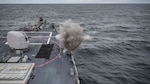 An MK 45 5-inch gun fires a round