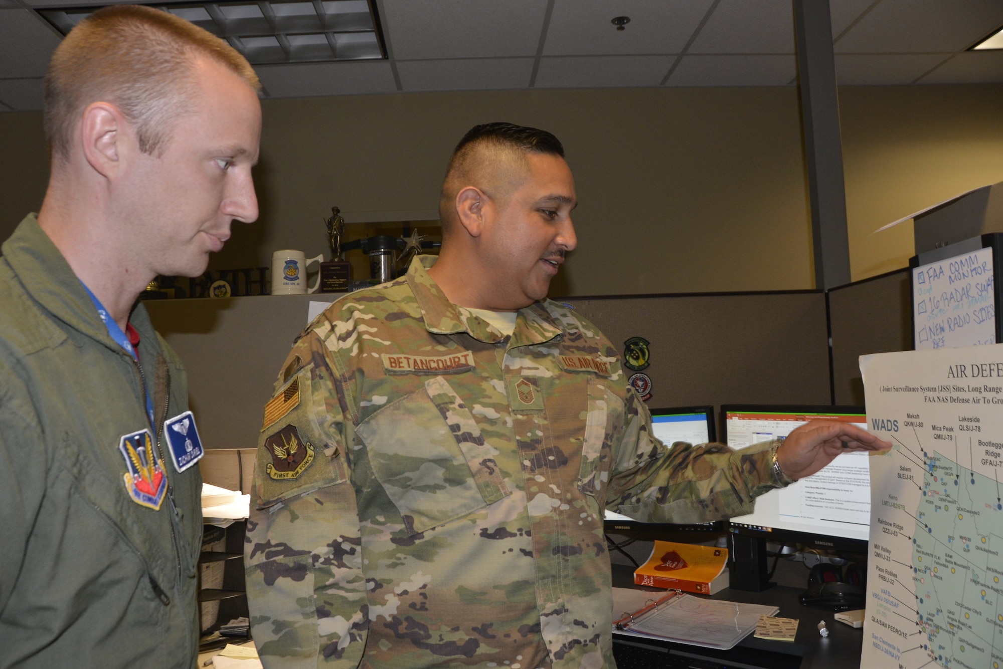 Capt. Zachary Darnell and Senior Master Sgt. Ricardo Betancourt, Air, Space and Information Operations Directorate, discuss air-defense operations. (Photo by Mary McHale)