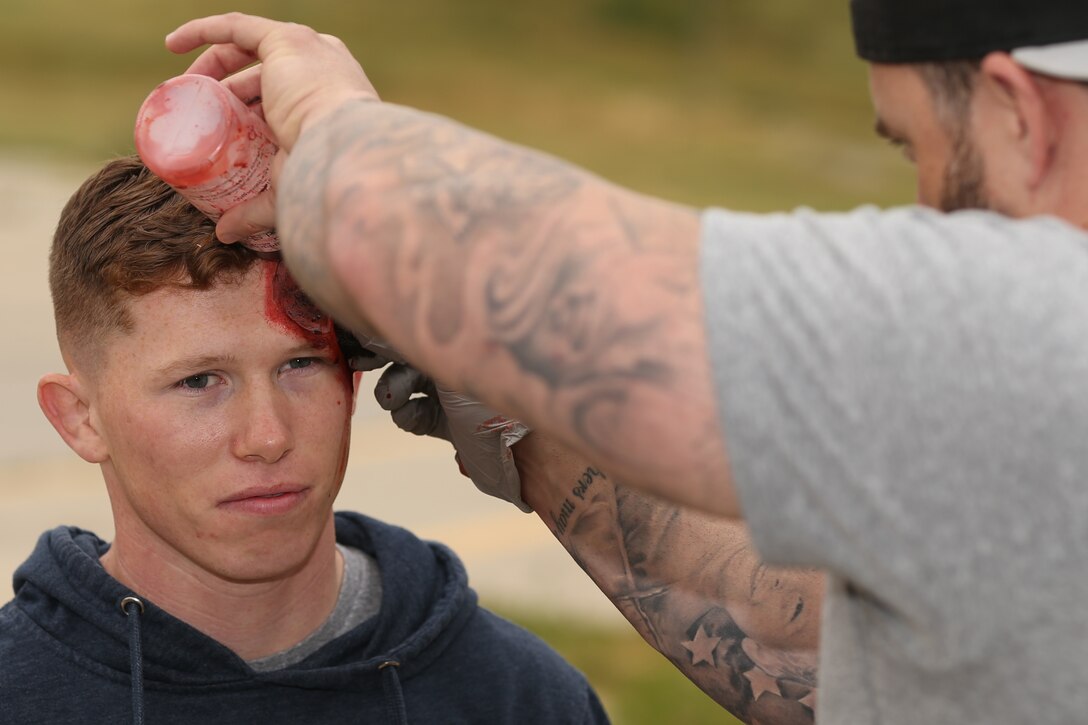 U.S. Marine Corps Lance Cpl. Payten Batalden (left), correctional specialist, 3rd platoon, Brig Company, Security and Emergency Services Battalion, Marine Corps Installations West, Marine Corps Base (MCB) Camp Pendleton gets a simulated bullet wound applied to his head by Chad Clawson, simulation operations specialist, Naval Hospital Camp Pendleton, during Exercise Semper Durus on MCB Camp Pendleton, California, April 9, 2019. Simulation operations specialists create realistic, simulated wounds for training exercises to ensure that the proper casualty assessment and care is being performed. (U.S. Marine Corps photo by Lance Cpl. Drake Nickels)