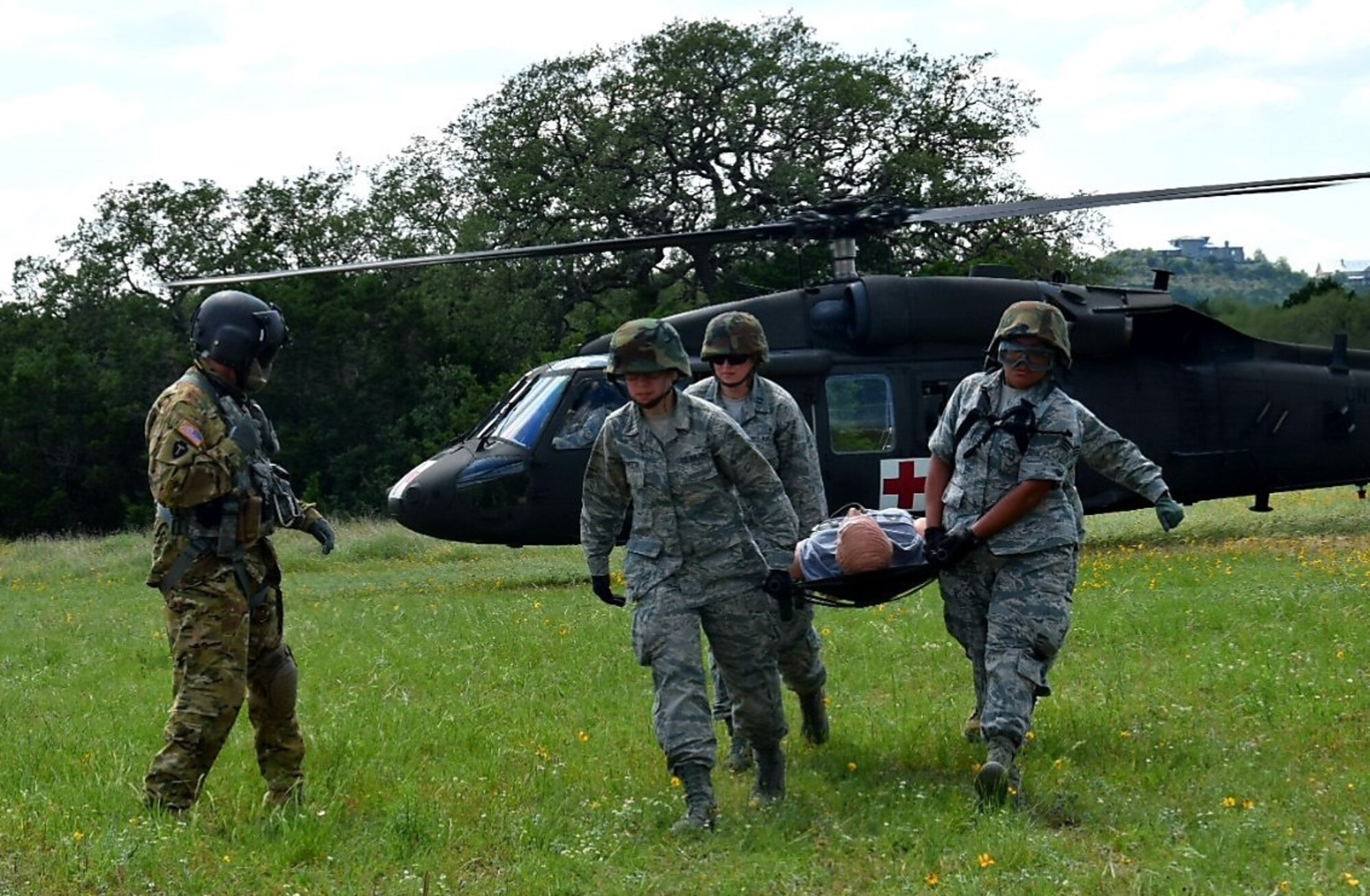 Sgt. 1st Class Dion Cortez, Company C, 2-149 Aviation Texas Army National Guard flight medic, guides medical technicians off-loading a simulated wounded patient by stretcher during Operation Joint Medic at Joint Base San Antonio-Camp Bullis May 5. The simulated wounded patient was loaded onto a Humvee for transportation to an expeditionary medical support facility.
