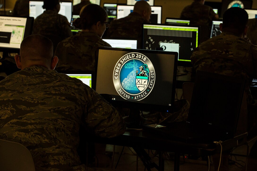 Service members look at laptop screens.
