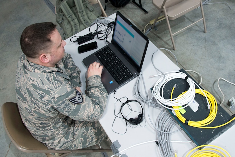 An overhead view of an airman working at a laptop.