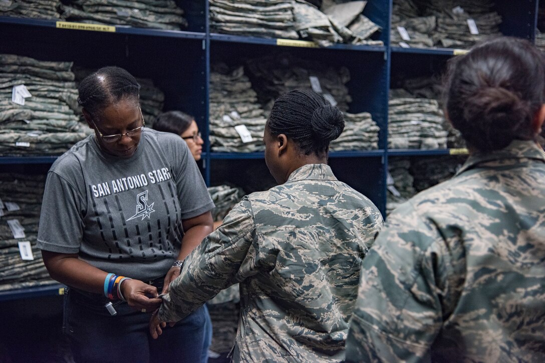 Vernalynne Carter, 502nd Logistics Readiness Squadron deputy section chief of clothing issue fits a trainee for her uniform during initial clothing issue May 1, 2019, at Joint Base San Antonio-Lackland, Texas. Between 300 and 400 trainees receive their first sets of uniforms weekly from initial clothing issue. (U.S. Air Force photo by Senior Airman Stormy Archer)