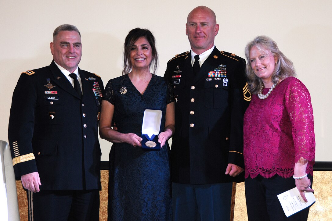 Four people stand in line for a posed awards photo.