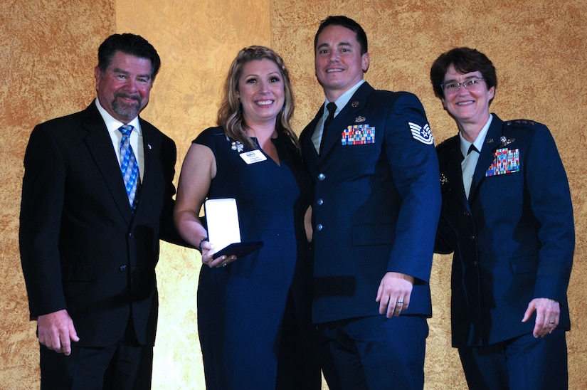 Four people stand in line for a posed awards photo.