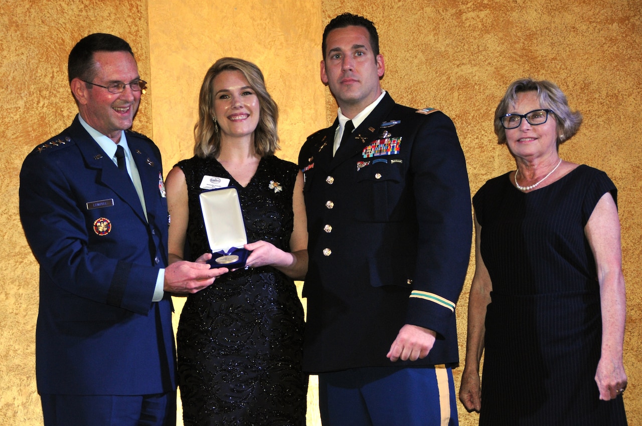 Four people stand in line for a posed awards photo.