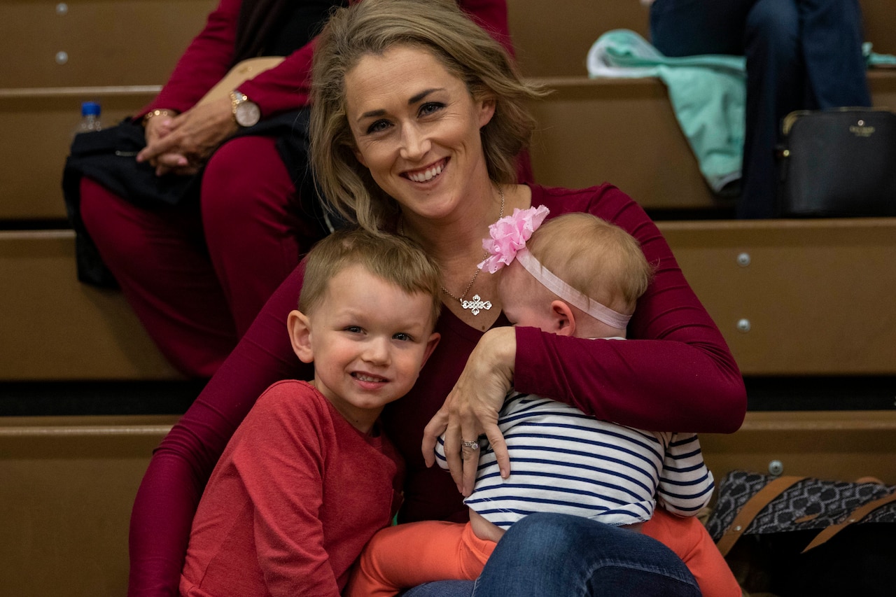 A mother waits for her soldier husband with her two children.