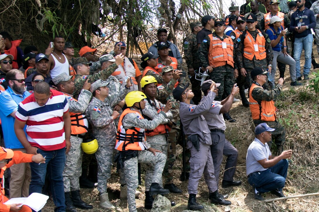 Representatives from Dominican Republic governmental and non-governmental agencies, alongside partner-nation military representatives, watch simulated water rescues take place in a river near Bajo Yuna, Dominican Republic May 9, 2019 as part of Fuerzas Humanitarias Humanitarias 2019.