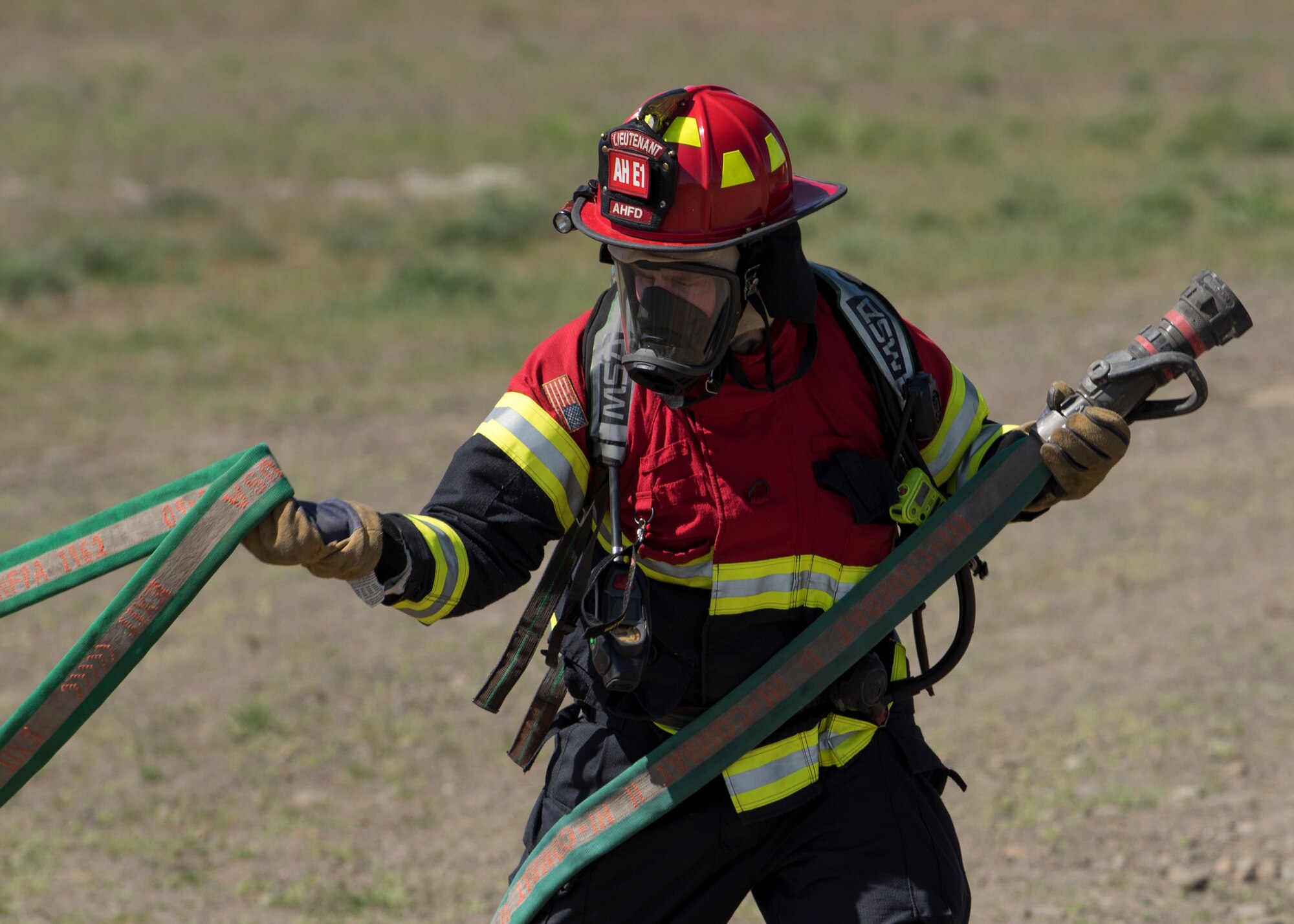 A firefighter from the Airway Heights Fire Department pulls out lengths of fire hose while preparing for a Major Accident Response Exercise drill near Fairchild Air Force Base, Washington, May 9, 2019.