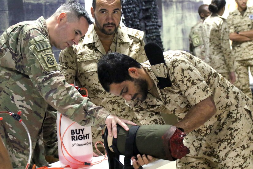 U.S. Army Col. Gregory Frazier, 8th Medical Brigade, holds a simulated limb as a medic in the Bahrain Defence Force applies a tourniquet during a medical subject matter expert exchange at the Crown Prince Center of Training and Medical Research in Bahrain April 15, 2019.