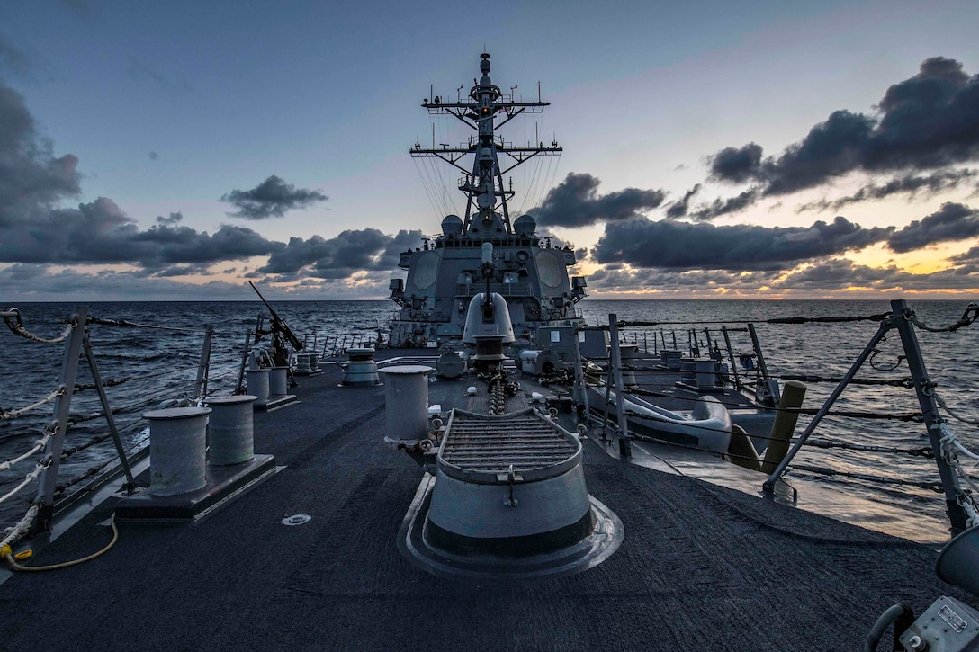 The deck of a ship looking out into the ocean with  ocean waters surrounding.